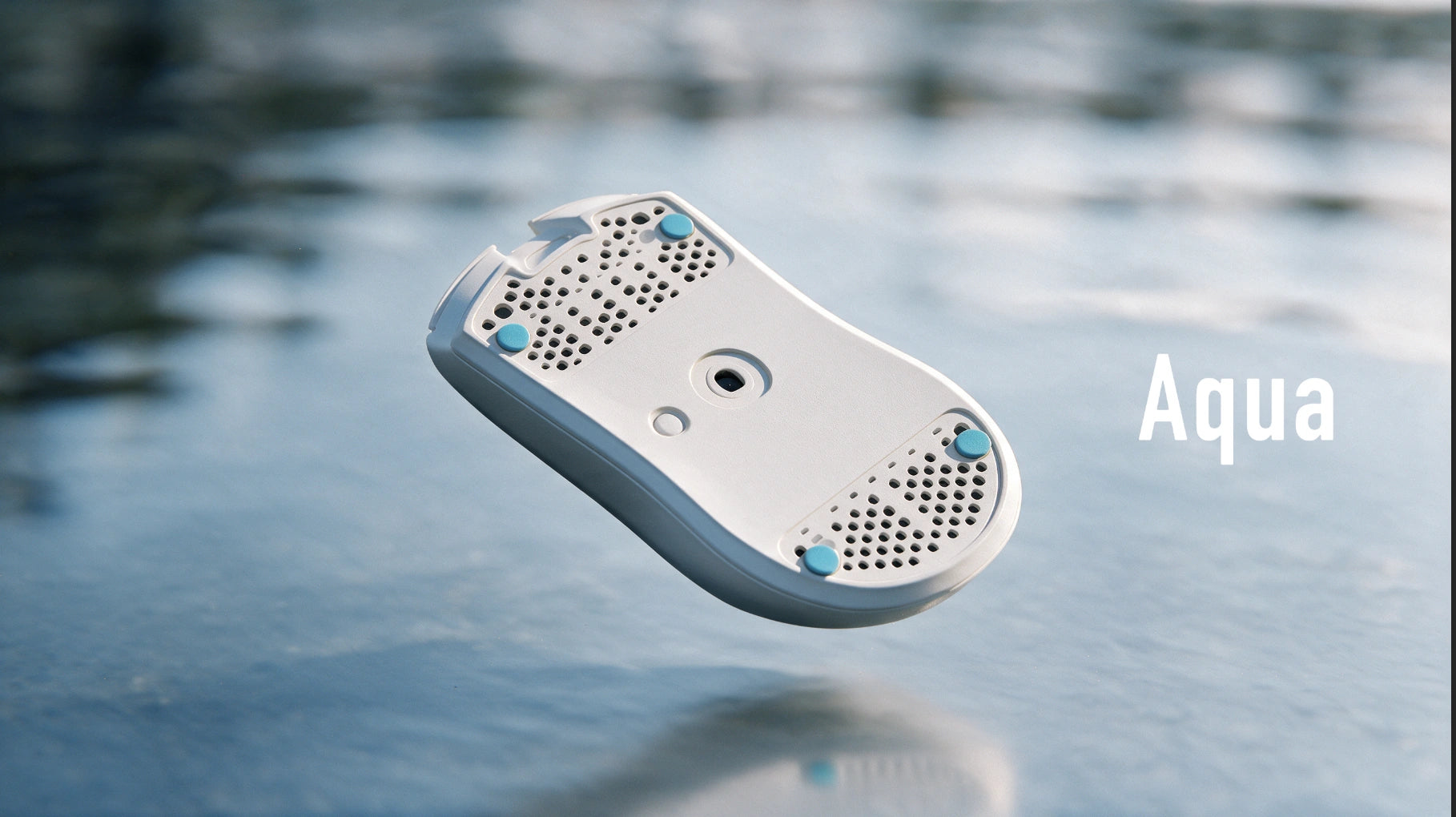 Aqua。青いPTFEソールを装着した白いマウス底面が、水面の上に浮かぶコンセプト画像。